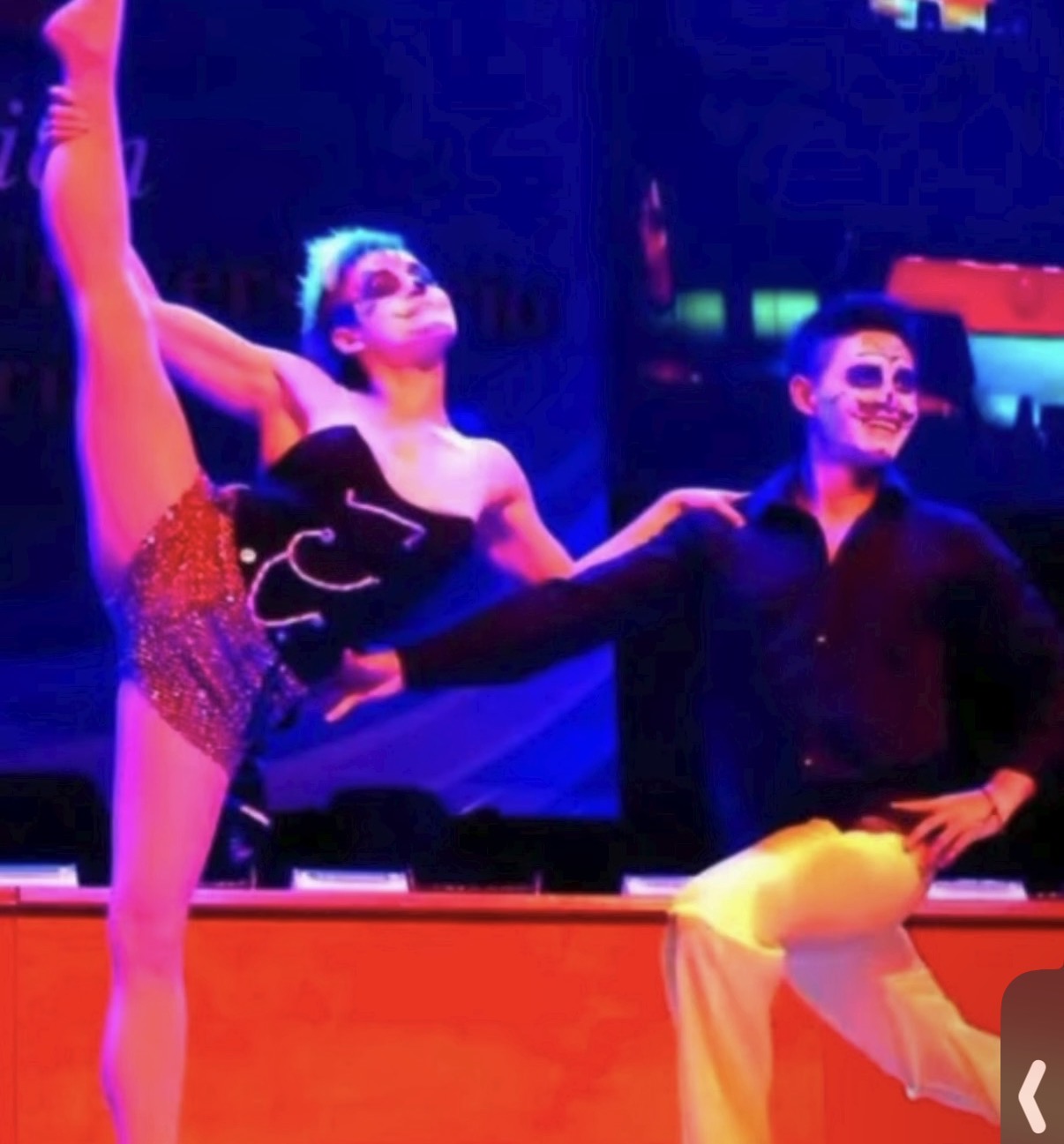 Two stage performers with skull face paint, one high kick