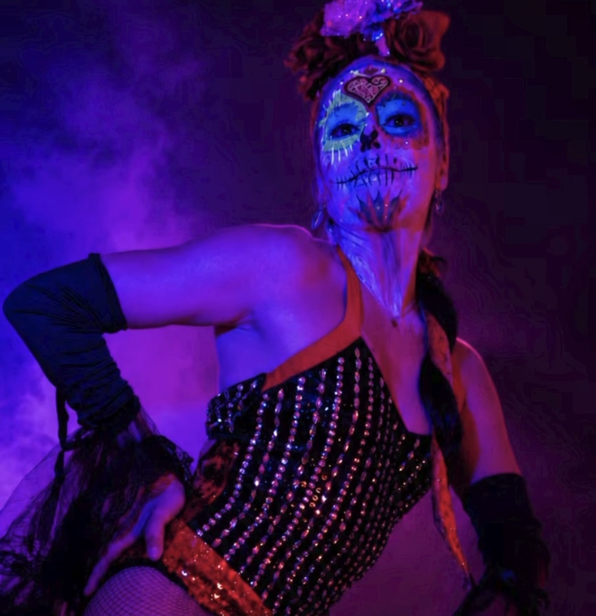 Sugar skull performer in black sequin outfit, purple smoke